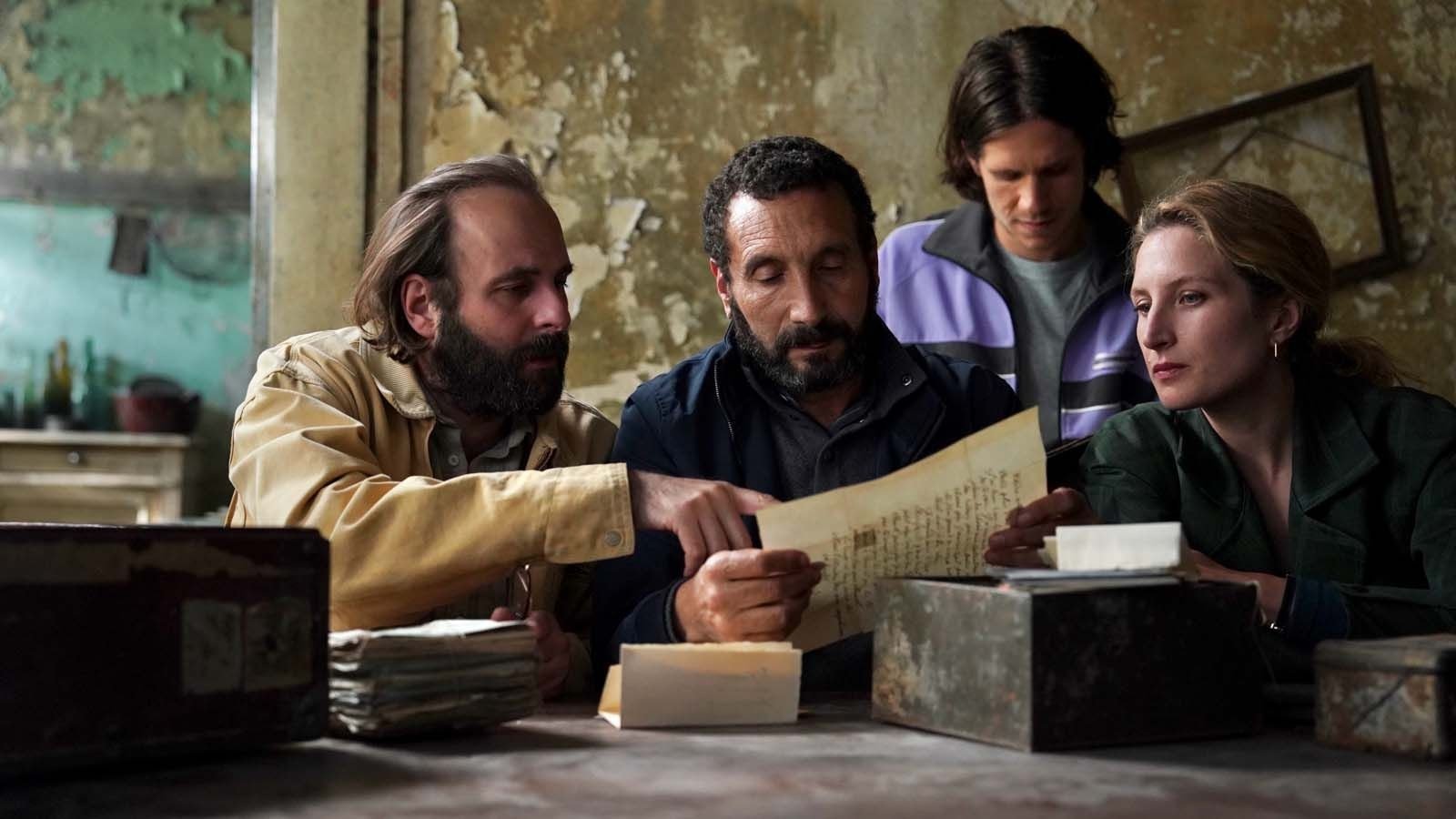 Vier Personen sitzen an einem Tisch und durchsuchen kleine Boxen.