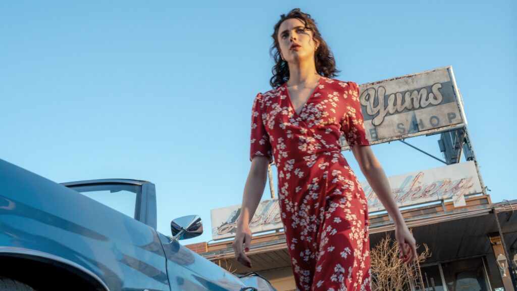 Honey (Margaret Qualley) läuft in einem rotn Kleid zu einem Auto.