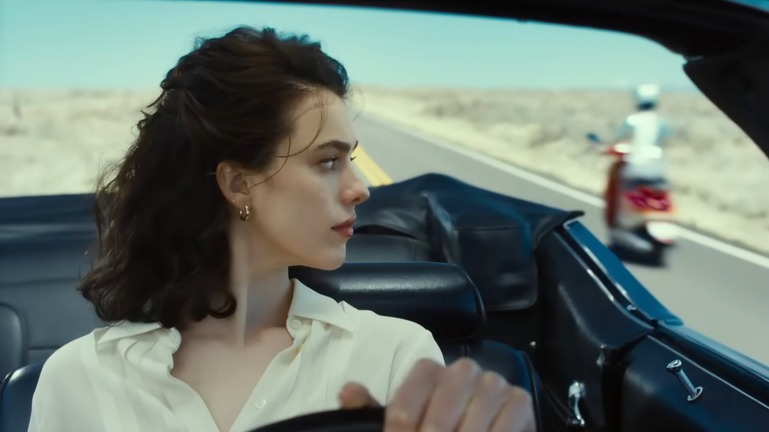 Honey sitzt auf einer Landstraße in einem Auto. Rechts fährt ein Moped vorbei.