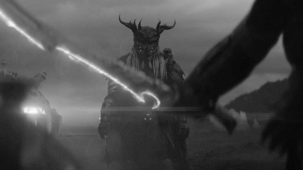 Ein Yautja mit Rüstung und Maske steht im Hintergrund und blickt auf eine Gestalt, von der man nur das Schwert im Vordergrund sieht | Predator: Badlands