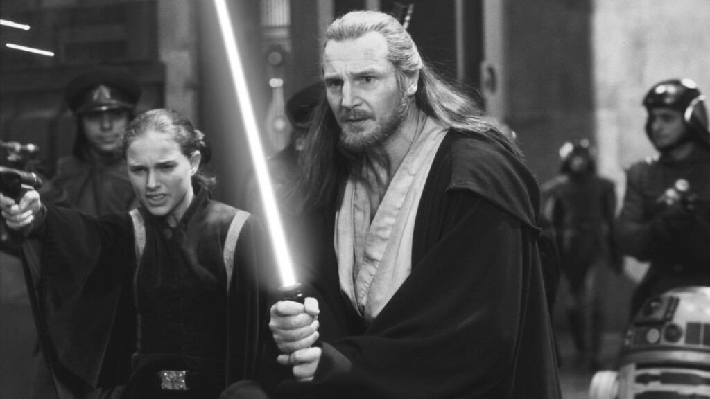 Qui-Gon Jinn (Liam Neeson) und Padme (Natalie Portman) stehen in einem Gang mit Soldaten. Qui-Gon hält ein Lichtschwert in beiden Händen. | Top 5 Technologien aus Filmen