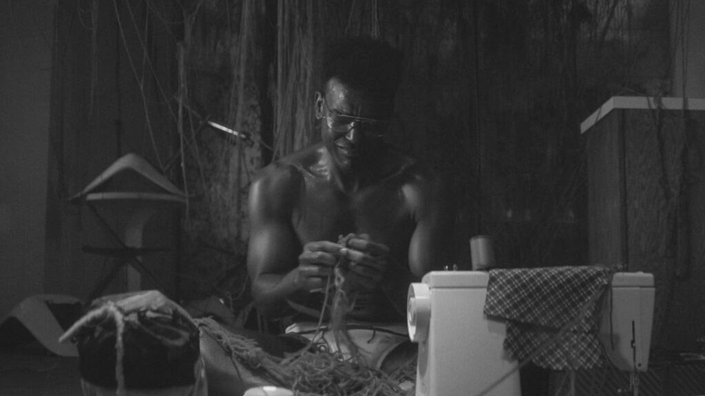 Das Bild zeigt einen Mann vor einer Wand sitzen und weinen. Er hält mehrere Wollfäden in der Hand. Das Bild ist aus der Serie "Them" | Media Monday #749