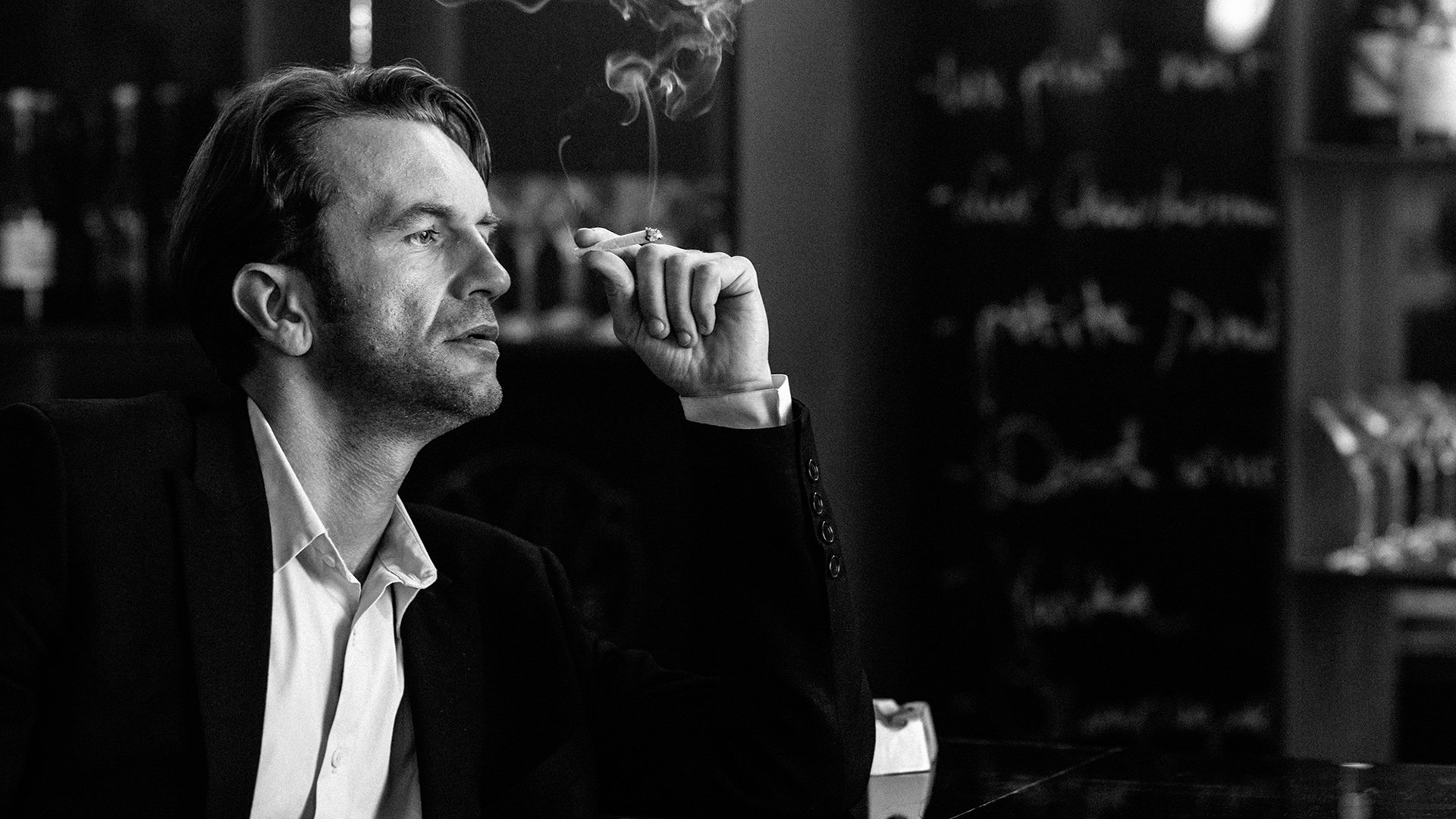 Wiktor (Tomasz Kot) sitzt an einer Bar und raucht eine Zigarette. | Monochrome Meisterwerke: 5 Arthouse Filme in Schwarz-Weiß