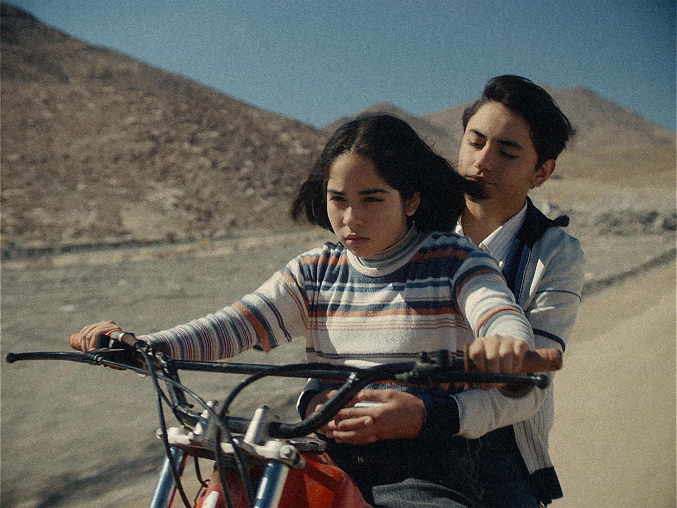 Das Bild zeigt Tamara Cortés mit einem Jungen auf einem Moped in einer Szene des Films Der geheimnisvolle Blick des Flamingos