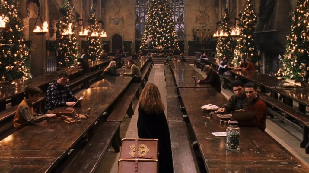 Das Bild zeigt die Große Halle aus "Harry Potter und der Stein der Weisen", Hermine betritt diese gerade, während mehrere Schüler verteilt an den Tischen sitzen | Die 5 besten Familienfilme für die Feiertage