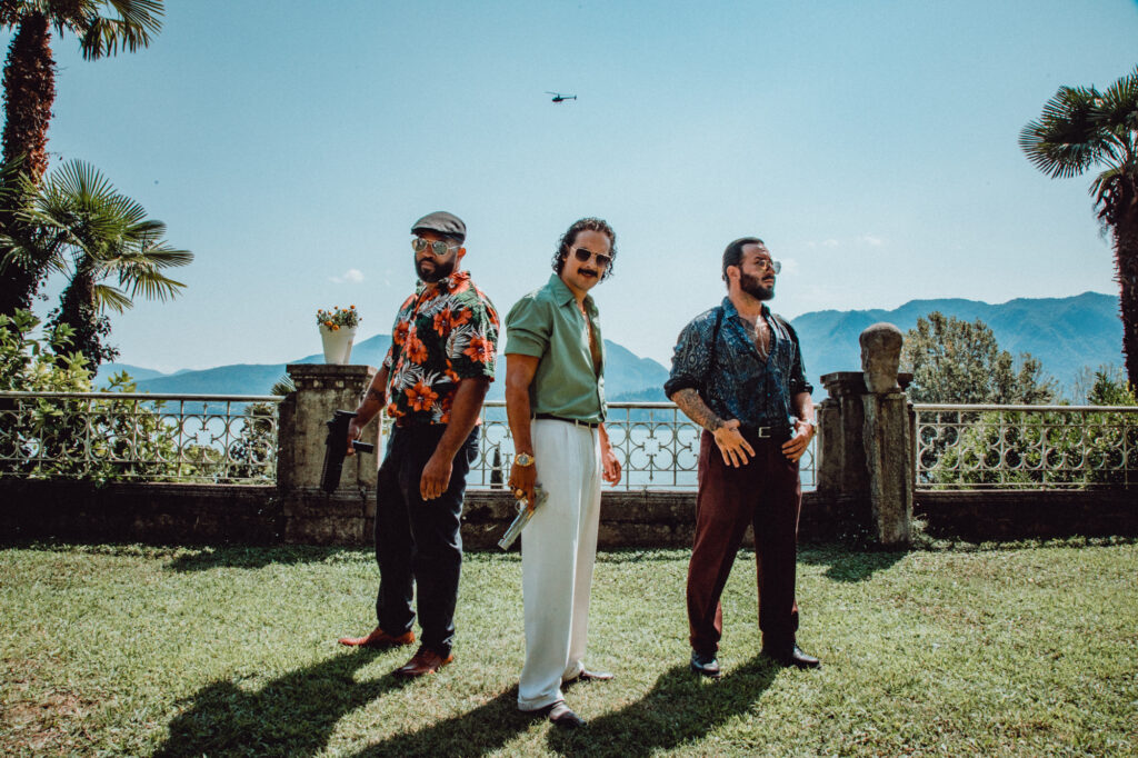 Das Bild zeigt Erkan Acar mit Pistole und umringt von zwei weiteren Personen in einer Szene des Films Make Me Feel