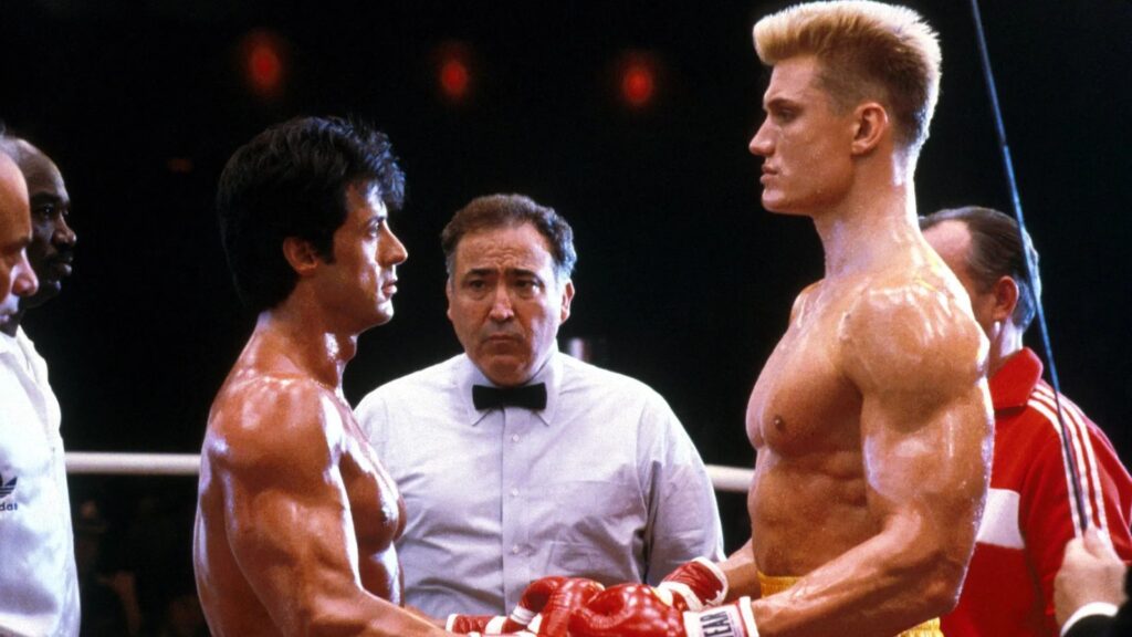 Rocky Balboa (Sylvester Stallone) und Ivan Drago (Dolph Lundgren) stehen sich im Ring gegenüber, der Ringrichter steht dahinter  | Die 5 besten Box- und Kampfsportfilme