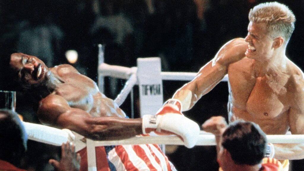 Ein harter Schlag im Boxring von Ivan Drago (Dolph Lundgren) gegen Apollo Creed (Carl Weathers)  | Die 5 besten Box- und Kampfsportfilme