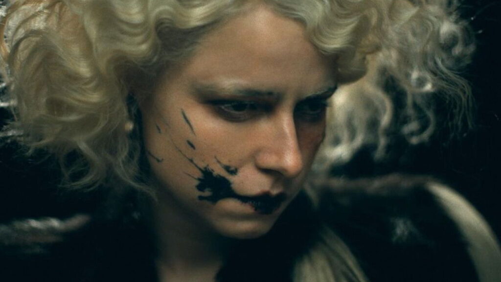 Jessie Buckley schaut traurig nach unten. Sie hat auf der rechten Wange Farbflecken und hellblonde Haare. | Top 5 filmische Neustarts 2026