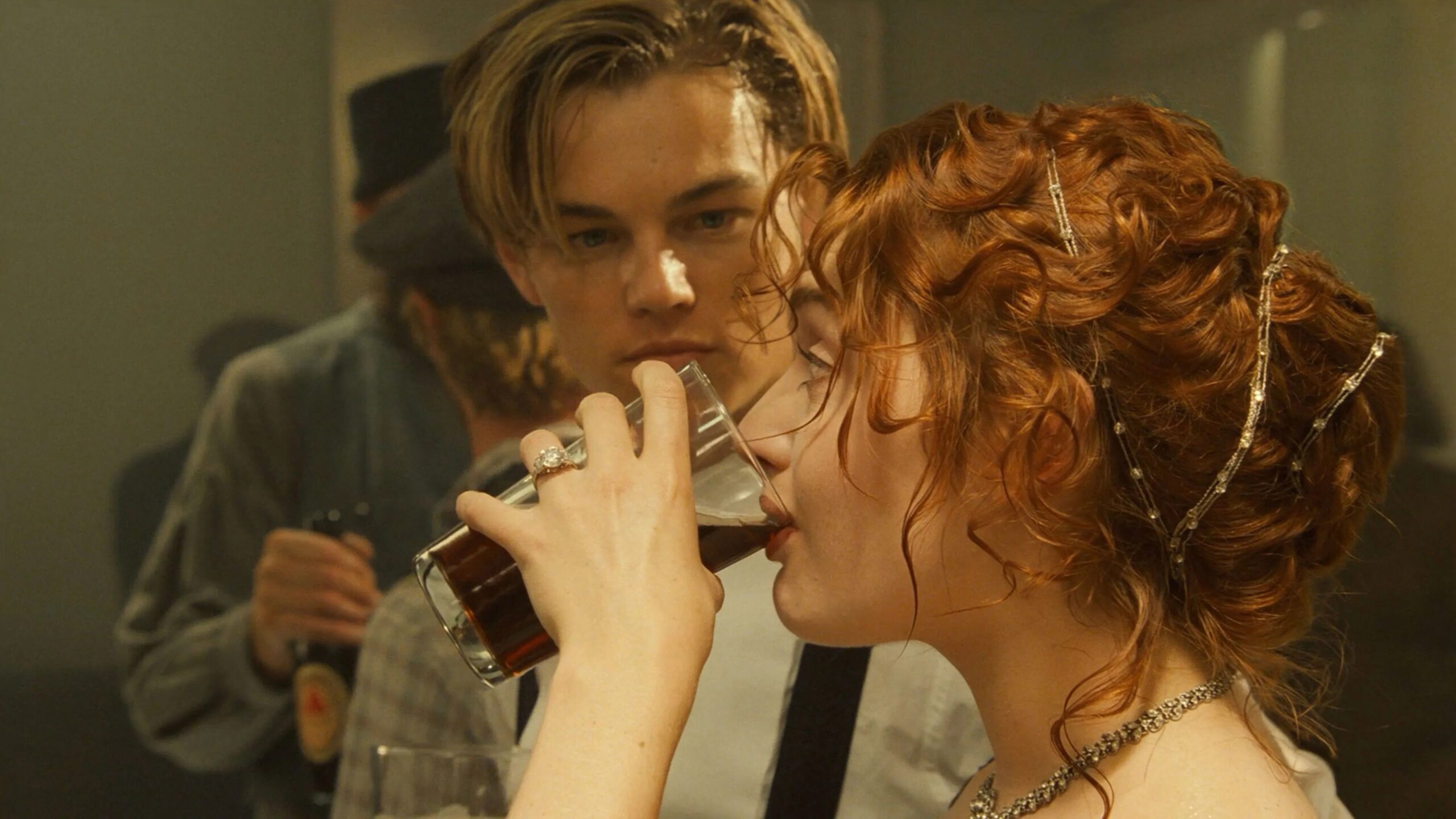 Das Bild zeigt einen erstaunten Jack (Leonardo DiCaprio), der Rose (Kate Winslet) dabei zu sieht, wie sie locker ein Bier runter kippt