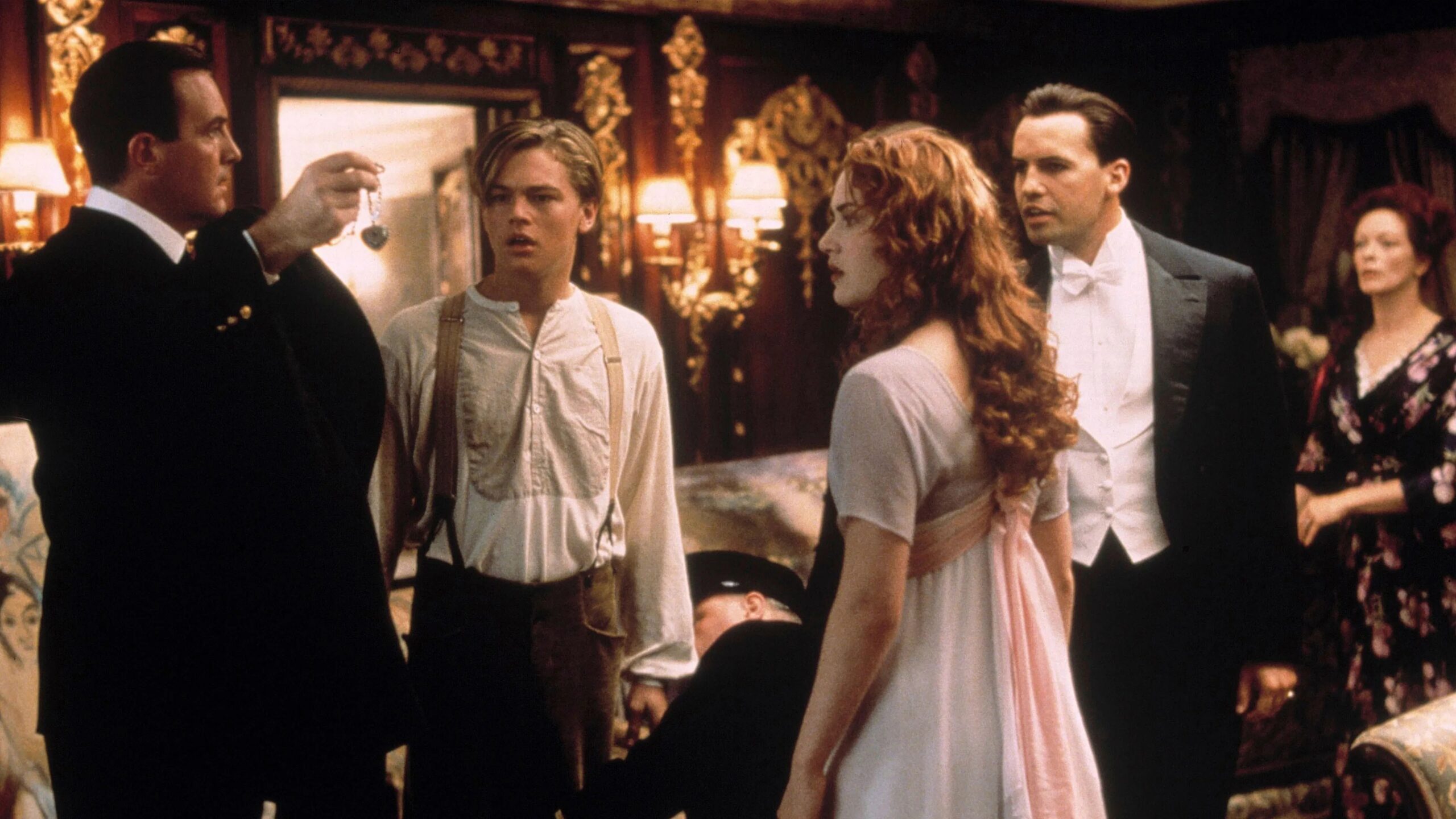 Das Bild zeigt Jack (Leonardo DiCaprio), Rose (Kate Winslet), Cal (Billy Zane), ihre Mutter Ruth (Frances Fisher) und den Bordpolizisten in Roses Suite. Der Polizist hält das Herz des Ozeans in der Hand und alle starren entsetzt darauf, denn Jack wird des Diebstahls beschuldigt