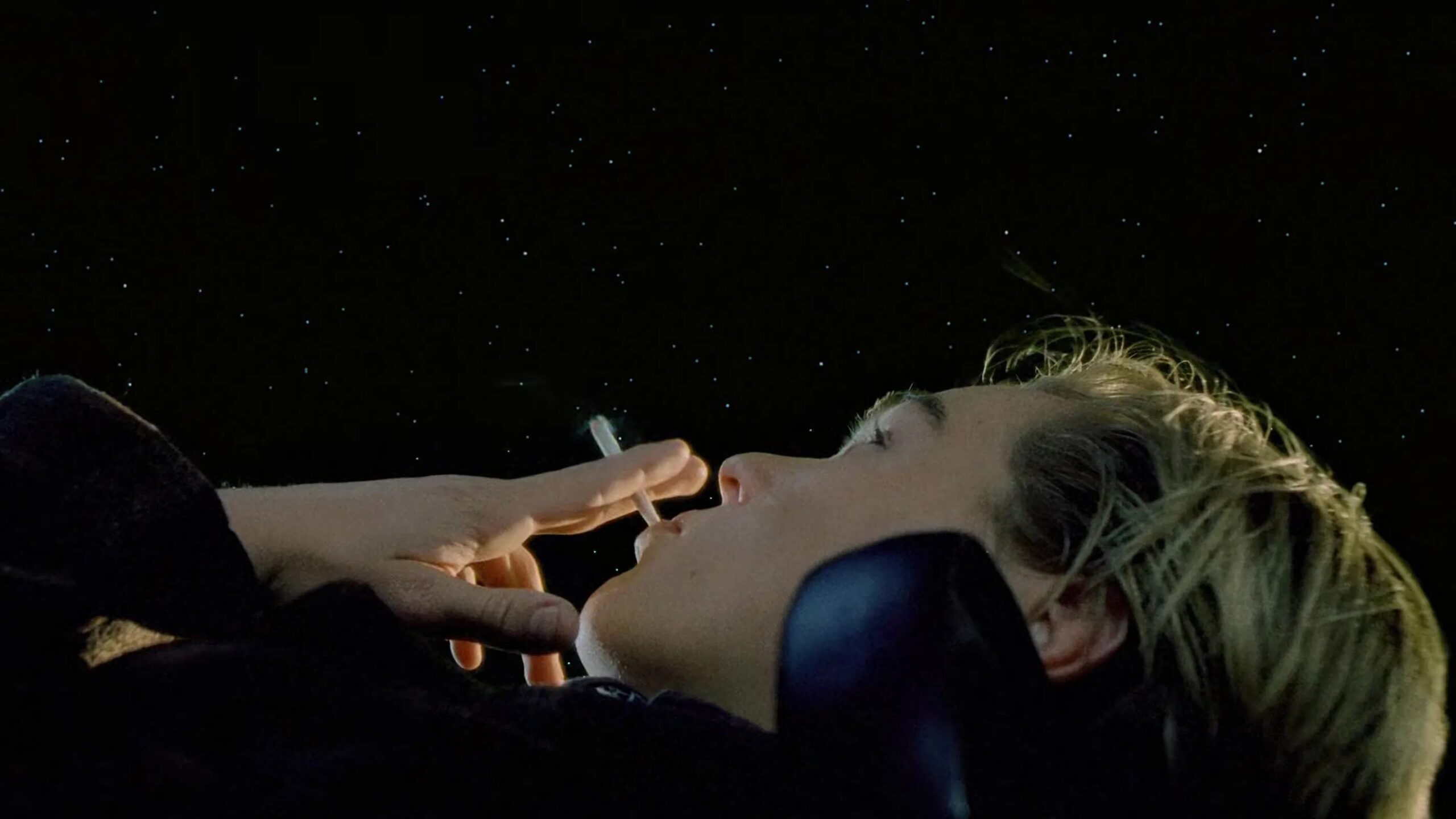Das Bild zeigt Jack Dawson (Leonardo DiCaprio) am Deck der Titanic. Er liegt auf einer Bank, raucht eine Zigarette und starrt verträumt in den Sternenhimmel