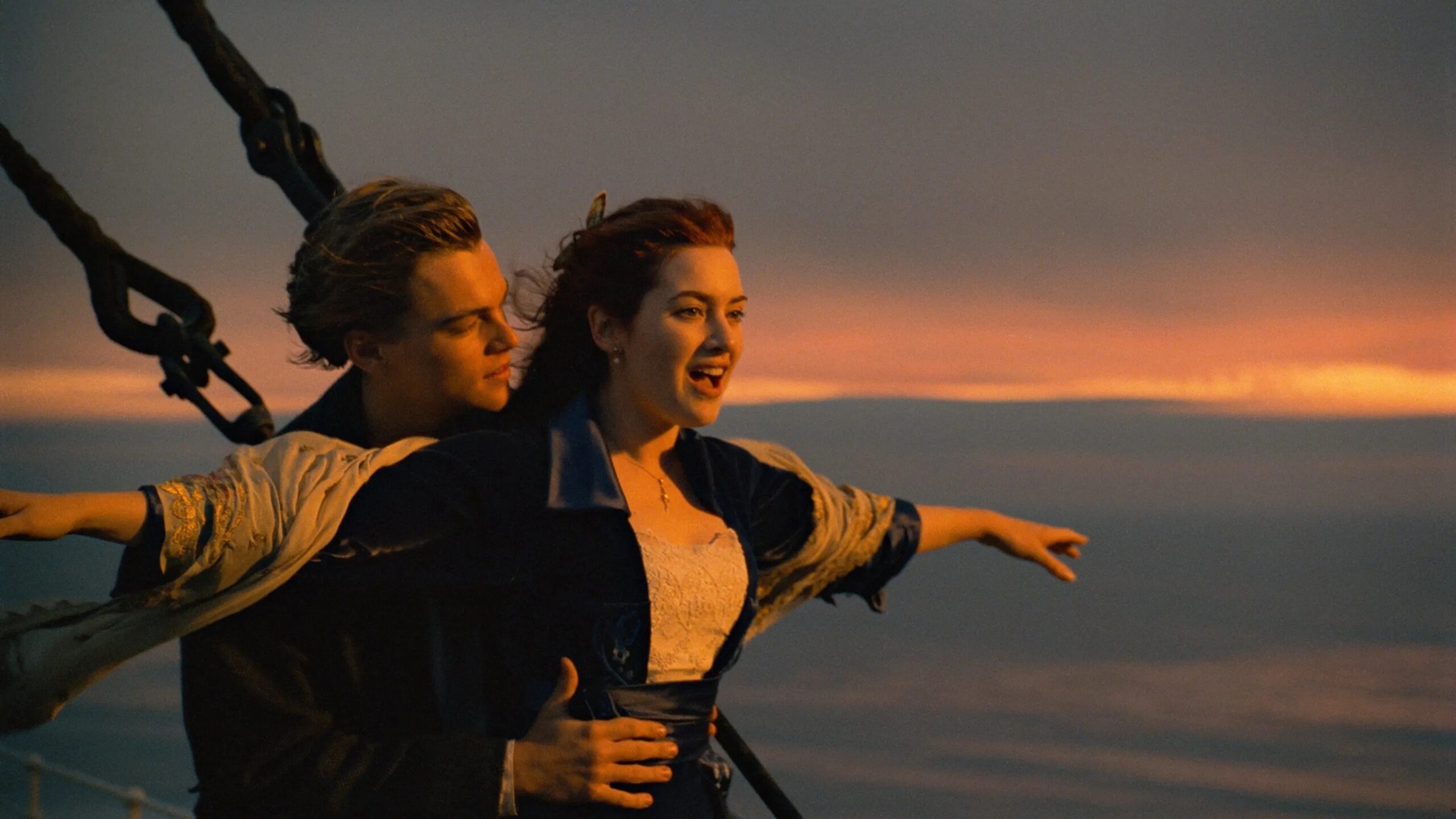 Das Bild zeigt Jack (Leonardo DiCaprio) und Rose (Kate Winslet) am Bug der Titanic, ausgelassen und frei