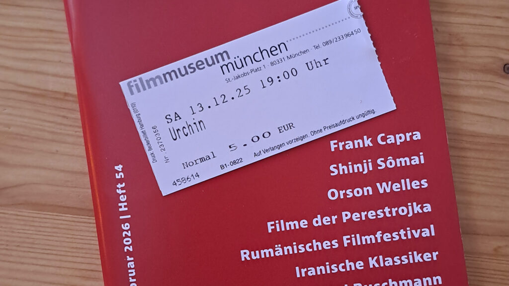 Das Bild zeigt ein Kinoheft und ein darauf liegendes Kinoticket zum Film Urchin im Filmmuseum München