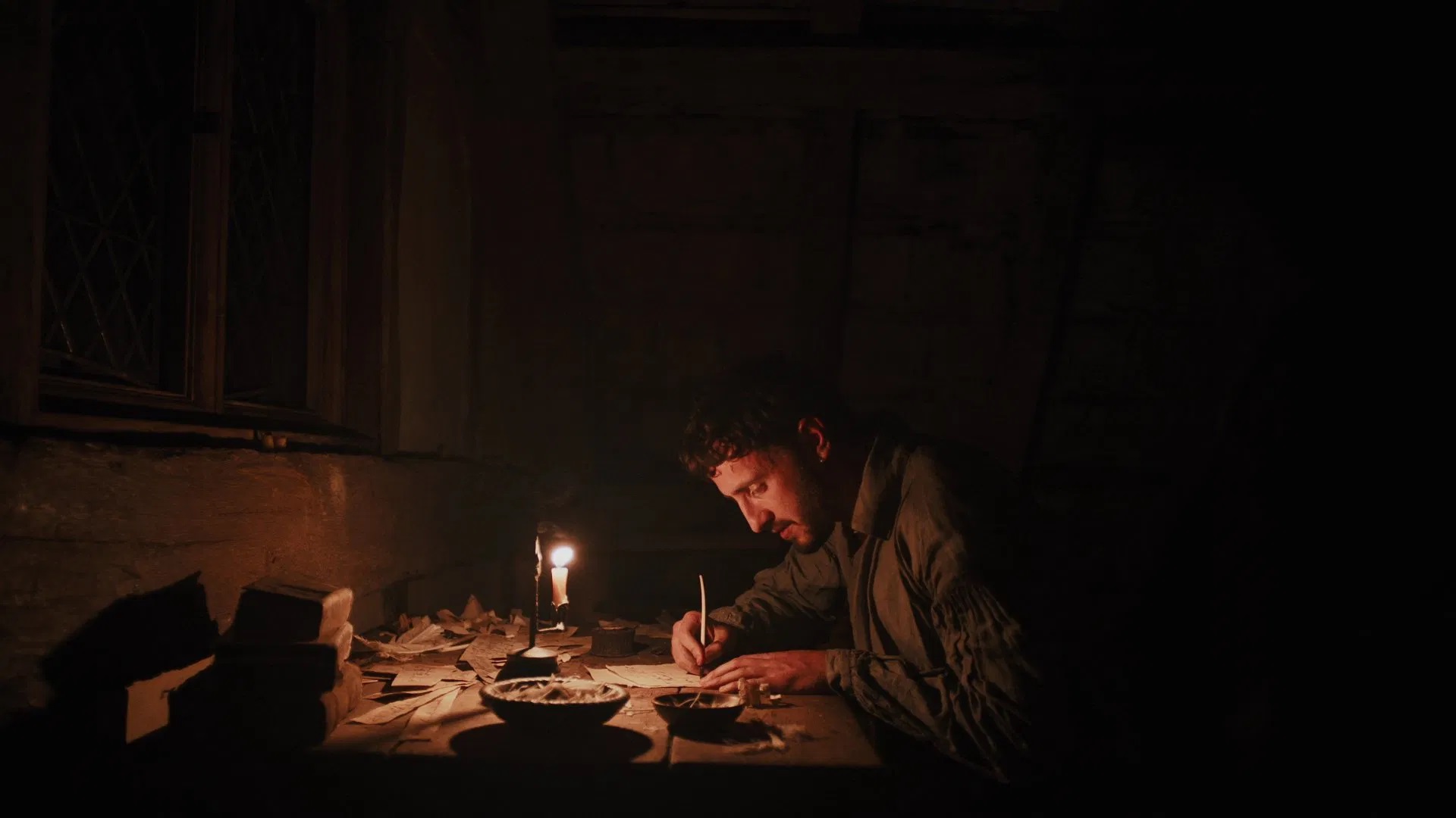 Das Bild zeigt William Shakespeare (Paul Mescal) schreibend am Schreibtisch