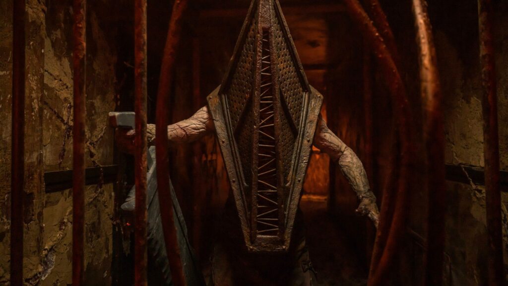 Das Bild zeigt das ikonische Monster "Pyramid Head" der durch verbogene Stangen auf die Kamera zukommt. | Return to Silent Hill