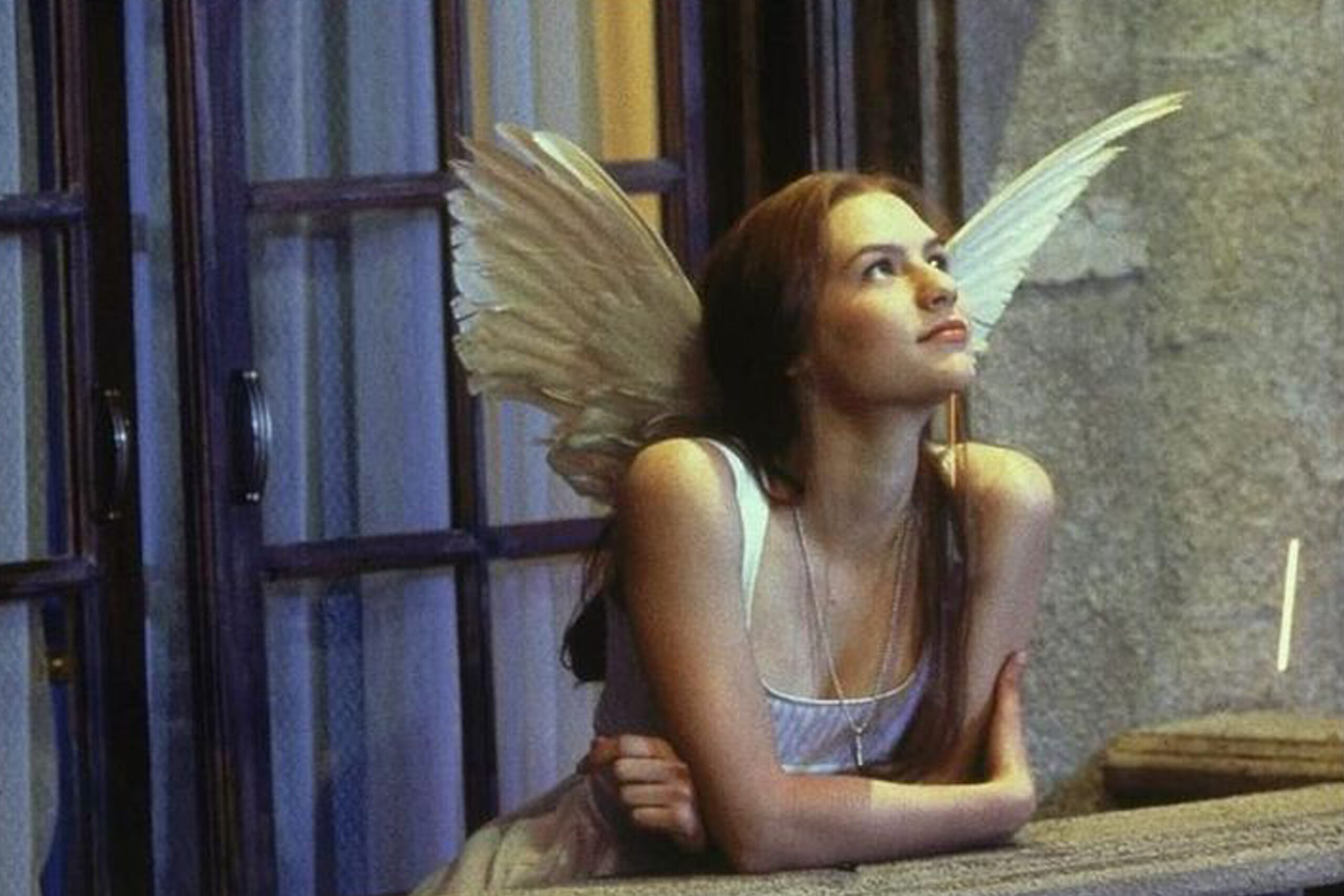 Das Bild zeigt Julia (Claire Danes) an der Brüstung ihres Balkons, in den Himmel blickend. Sie trägt ein weißes Kleid und Engelsflügel