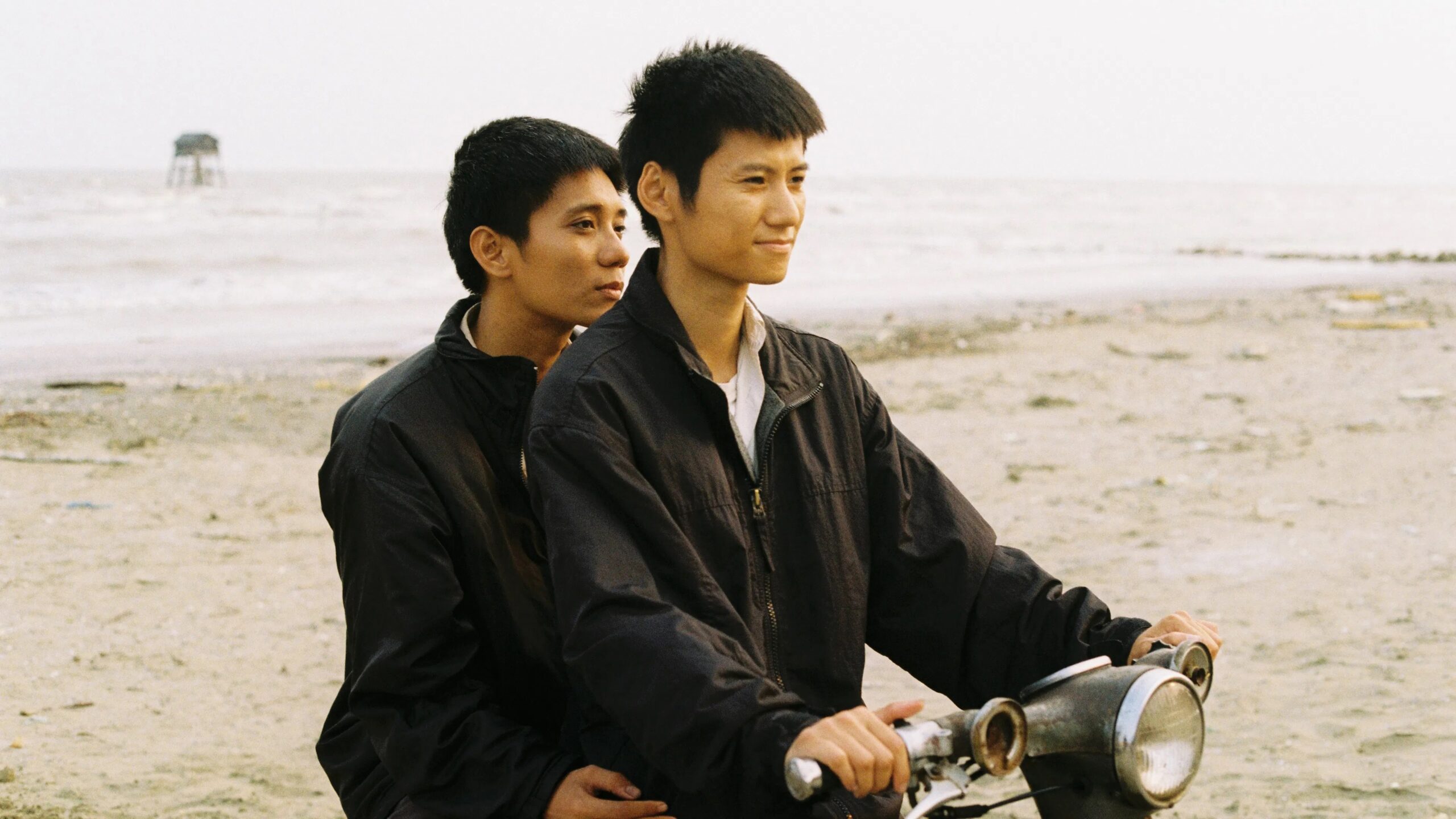 Das Bild zegt Nam (Phạm Thanh Hải) und Viet (Đào Duy Bảo Định) am Strand auf einem Moped sitzen