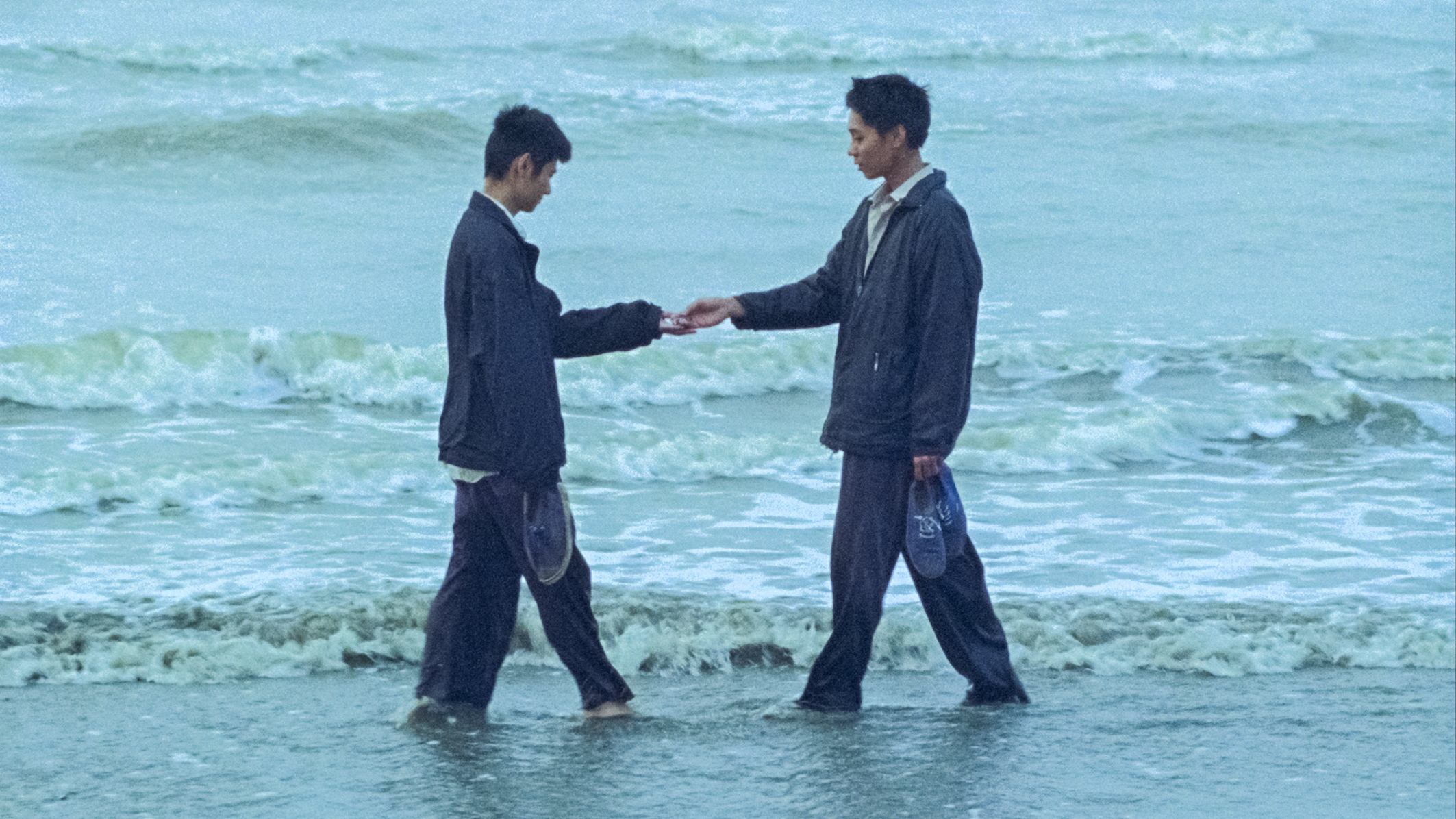 Das Bild zegt Nam (Phạm Thanh Hải) und Viet (Đào Duy Bảo Định) am Meeresufer im Wasser sich gegenüber stehend