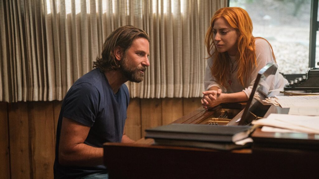 Lady Gaga und Bradley Cooper sitzen an einem Klavier, eine Szene aus "A Star is Born" | Die 5 besten Musik-Biopics
