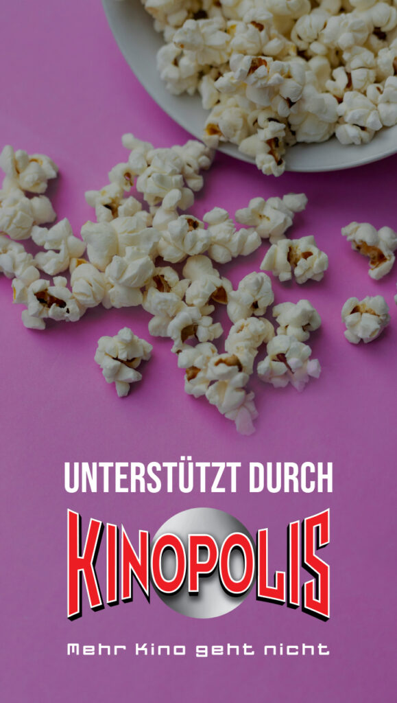 Nahaufnahme einer Schale mit Popcorn auf rosa Untergrund, daneben verstreute Popcornstücke. Unter dem Bild steht der Text ‚Unterstützt durch Kinopolis – Mehr Kino geht nicht