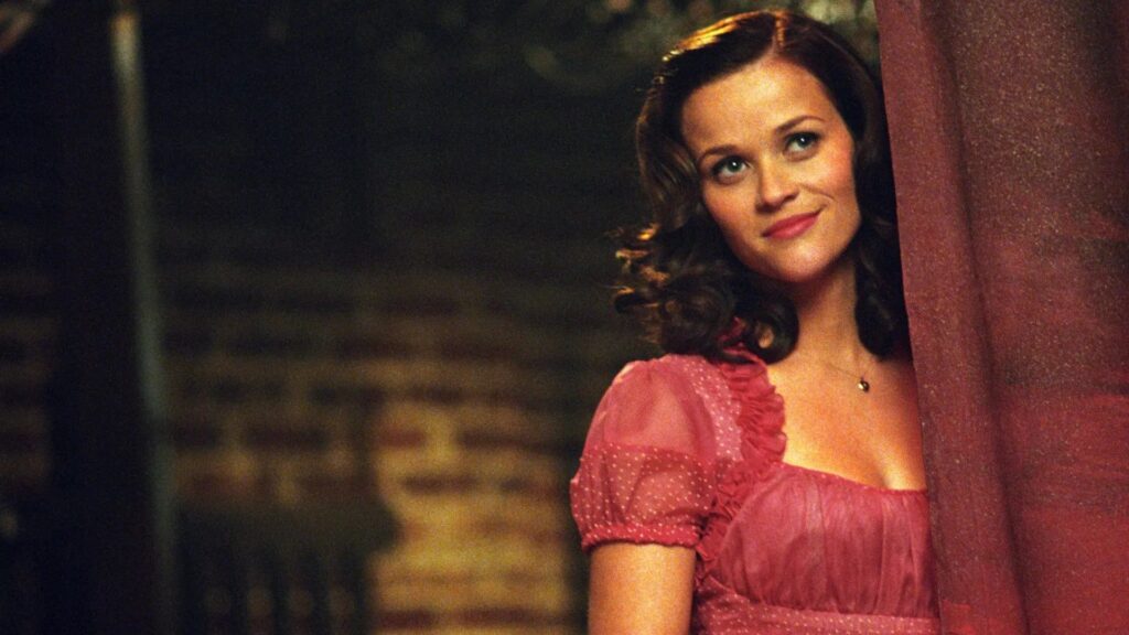 Reese Witherspoon als June Carter Cash schaut hinter einem Bühnenvorhang hervor und lächelt