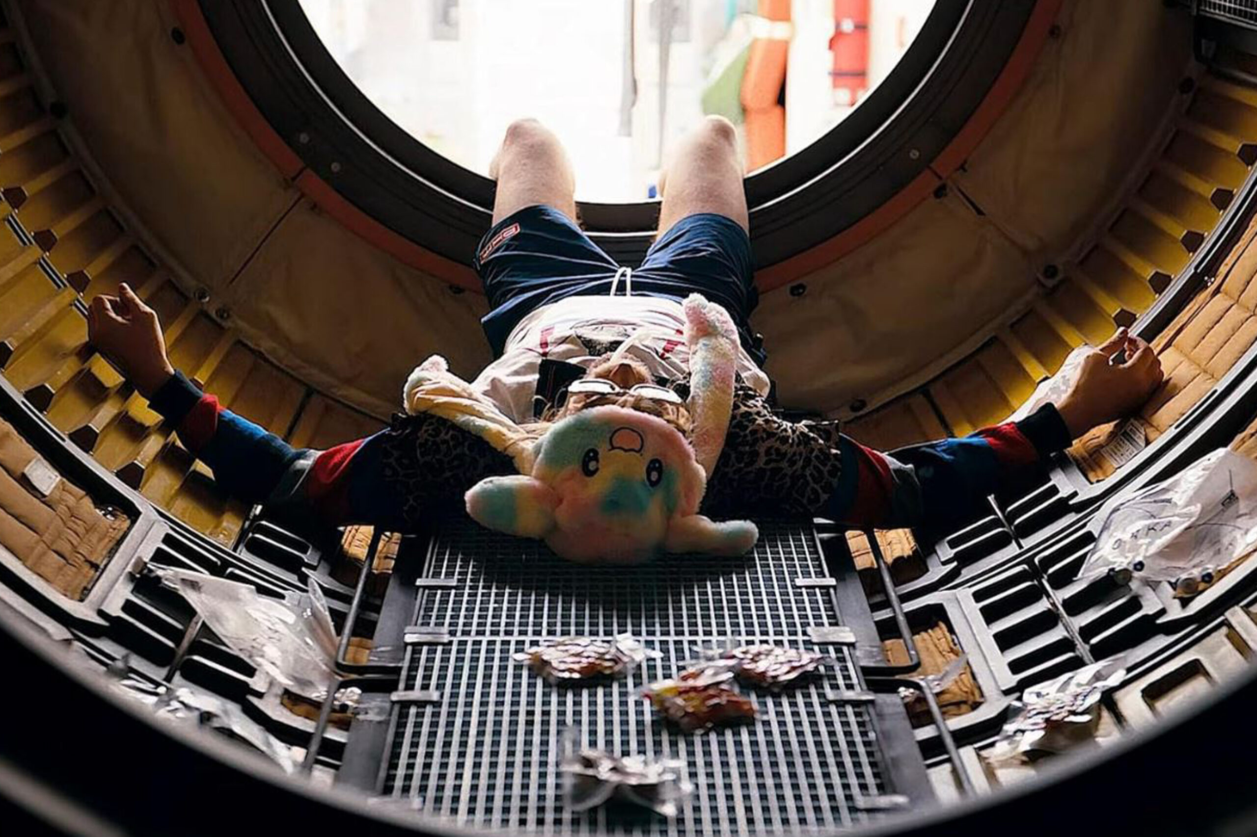 Ryan Gosling als Ryland Grace liegt in einer metallischen Kapsel mit verstreuten Gegenständen und witziger, bunter Häschen Mütze. Er ist offensichtlich betrunken