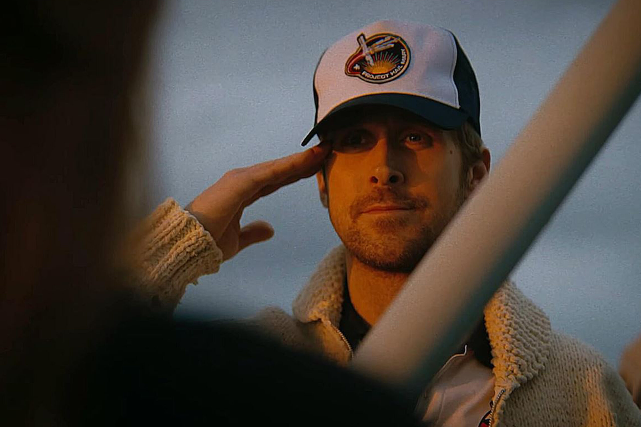 Ryan Gosling als Ryland Grace salutiert mit Project‑Hat‑Kappe im warmen Licht, Szene aus Der Astronaut.