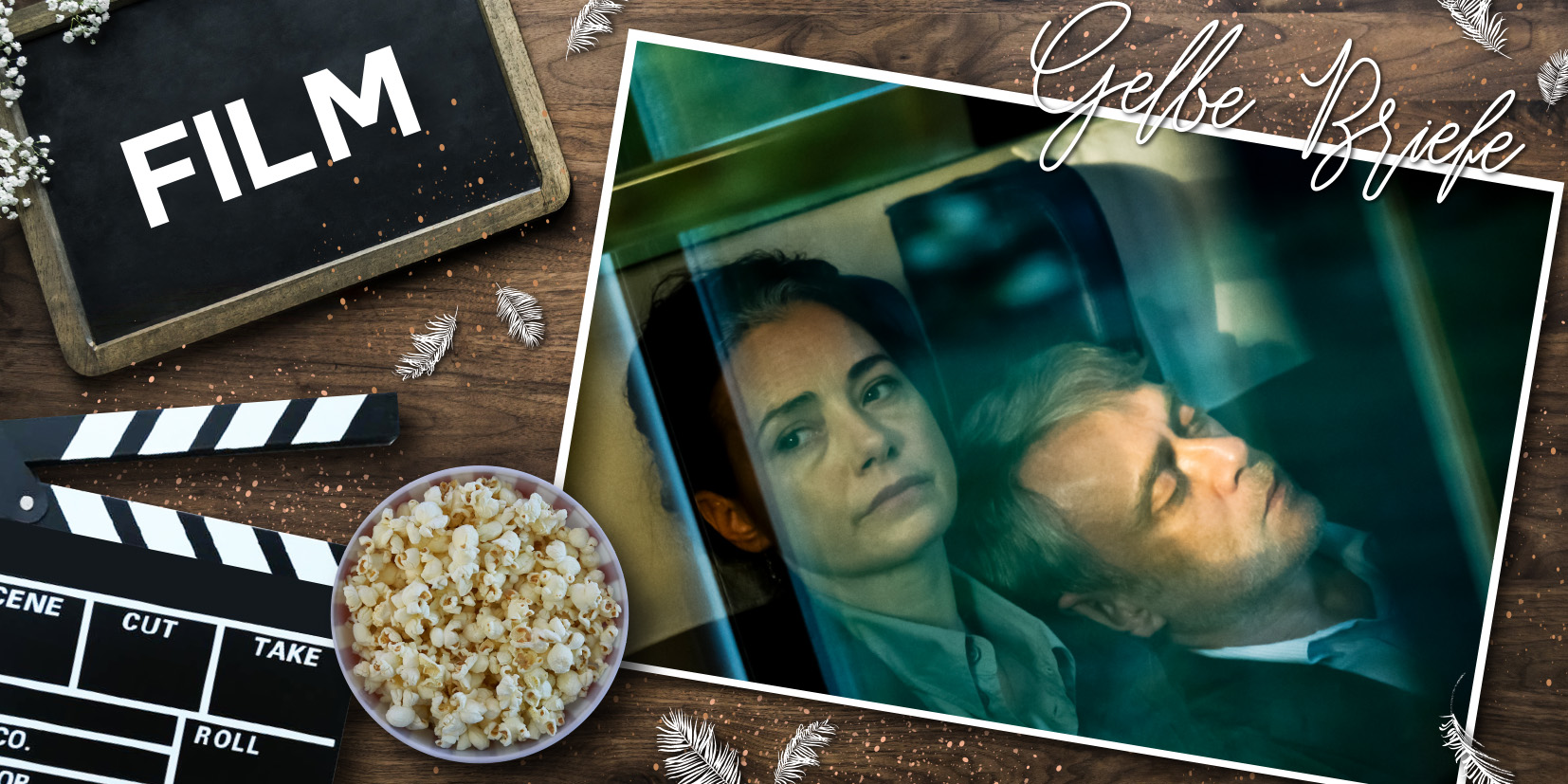 Filmklappe mit der Aufschrift ‚Film‘ und einer Schale Popcorn auf Holzuntergrund; daneben ein Foto zweier eng beieinandersitzender Personen hinter einem Fenster mit dem handschriftlichen Titel ‚Gelbe Briefe‘.