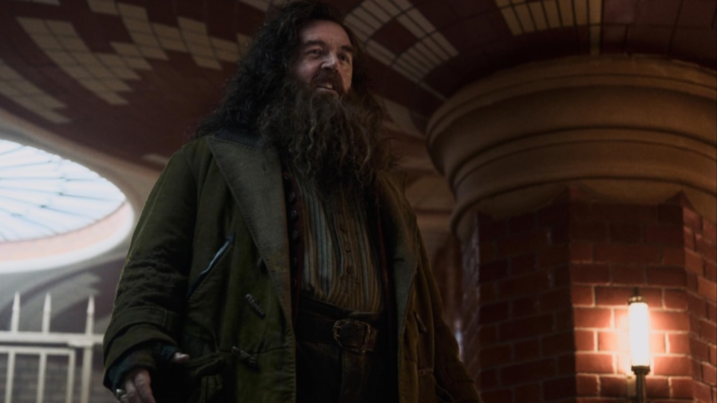 Rubeus Hagrid (Nick Frost) steht groß aufgebaut da und lächelt freundlich