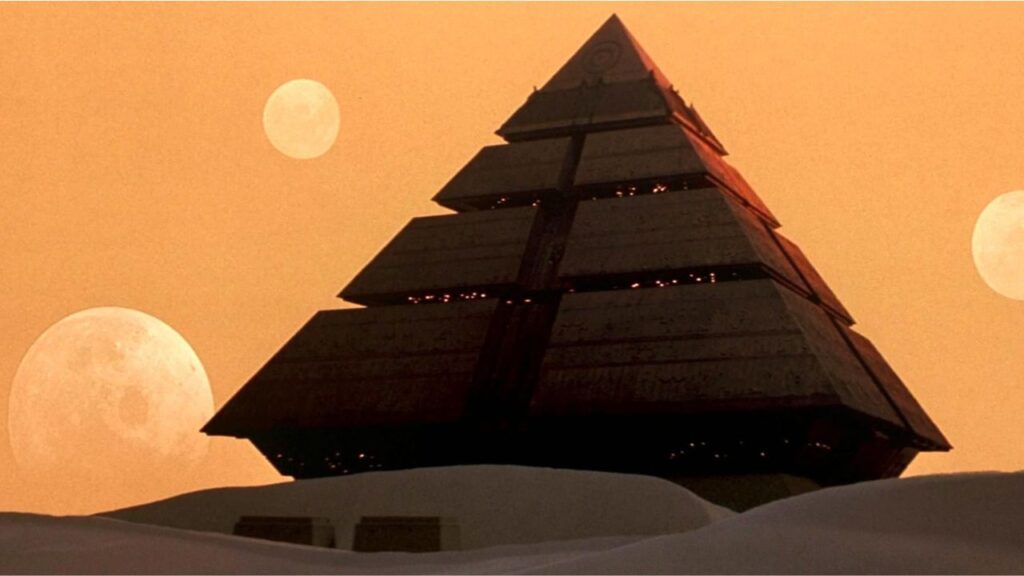 Ein riesiges pyramidenförmiges Raumschiff in einer Wüste. Dahinter mehrere Planeten am Himmel. | Eure 5 liebsten Raumfahrzeuge