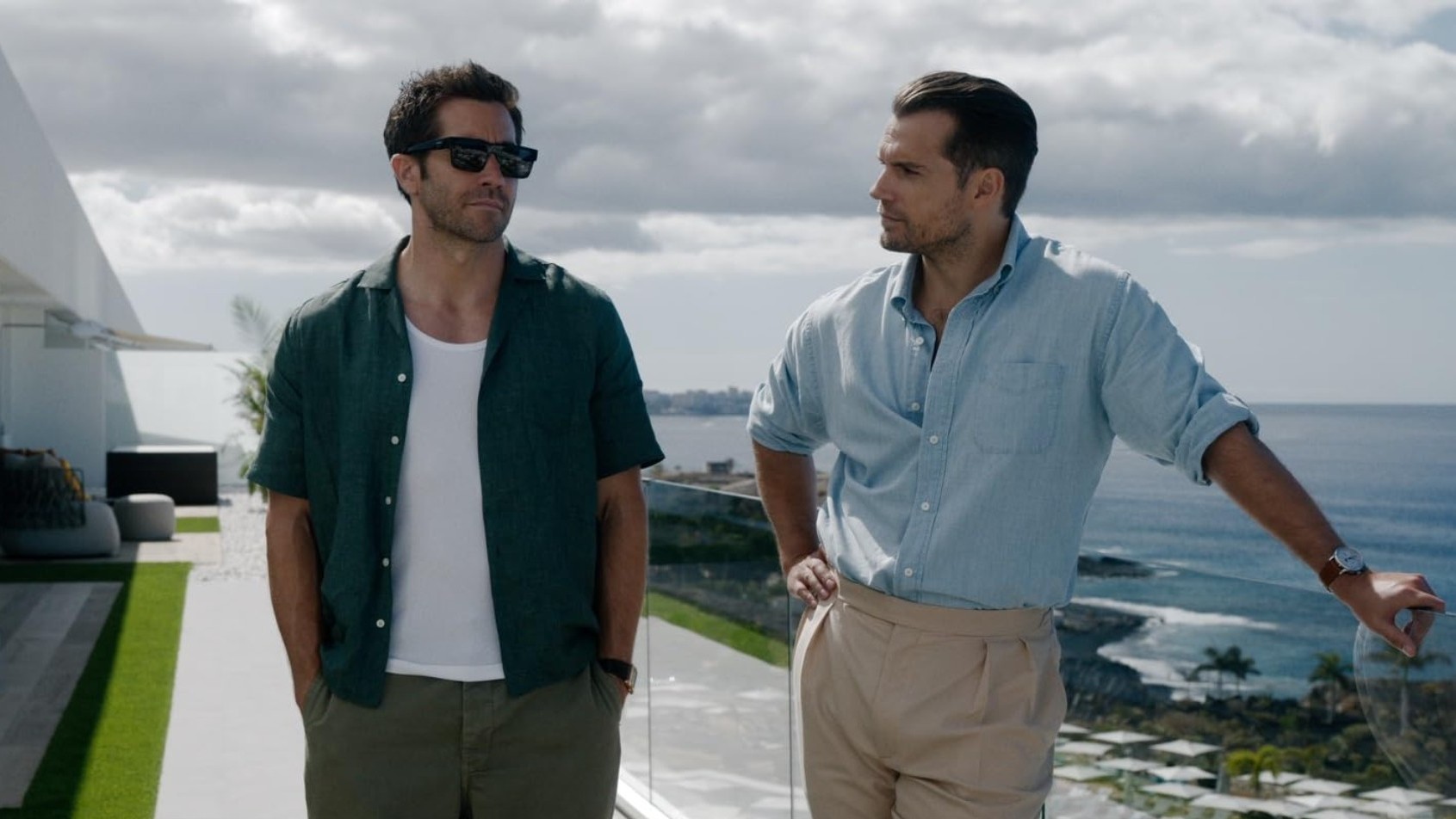 Bronco (Jake Gyllenhaal) und Sid (Henry Cavill) stehen auf der Terrasse einer Villa. Im Hintergrund in der Ferne ist das Meer zu sehen.
