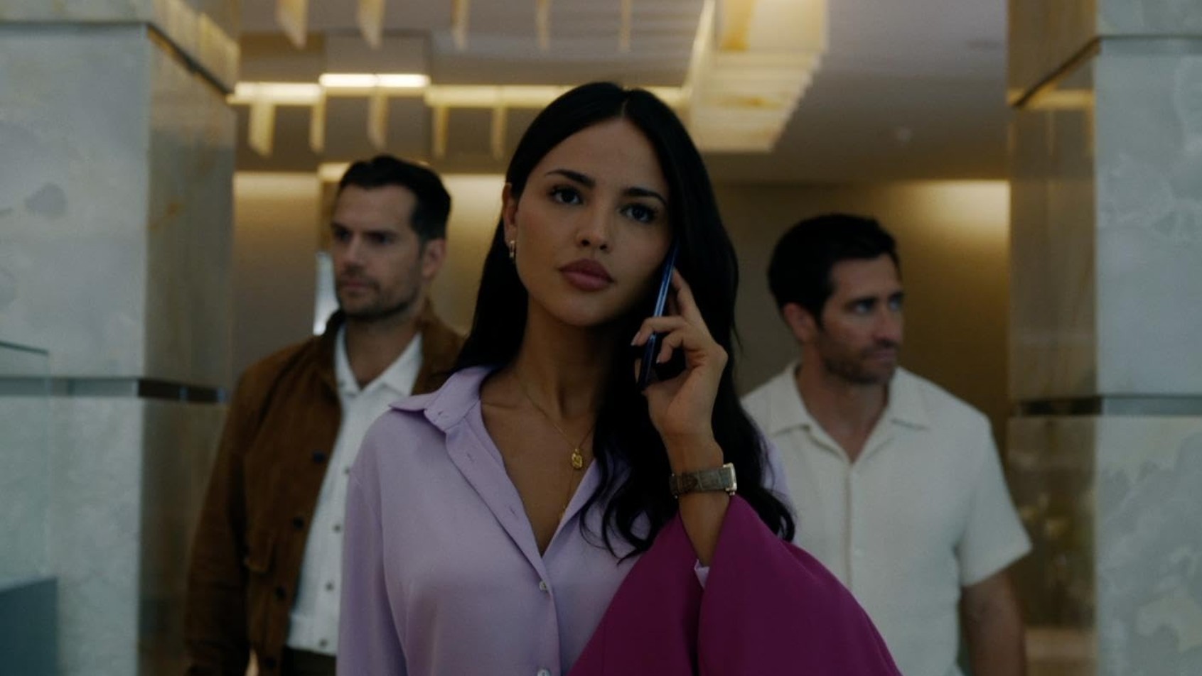 Sophia (Eiza González) hält ein Telefon an ihr Ohr. Im Hintergrund stehen Sid (Henry Cavill) und Bronco (Jake Gyllenhaal).