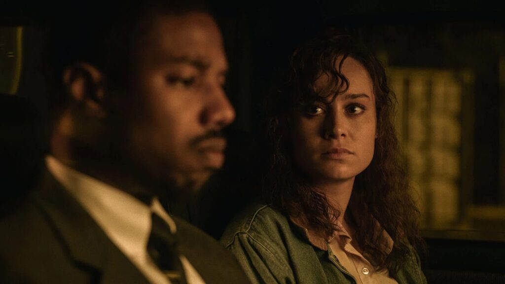 Michael B. Jordan und Brie Larson sitzen im Auto, Jordan ist im Profil im Vordergrund, Larson sieht in besorgt an - Eine Szene aus "Just Mercy" (2019) | Die 5 besten Justiz- und Gerichtsfilme