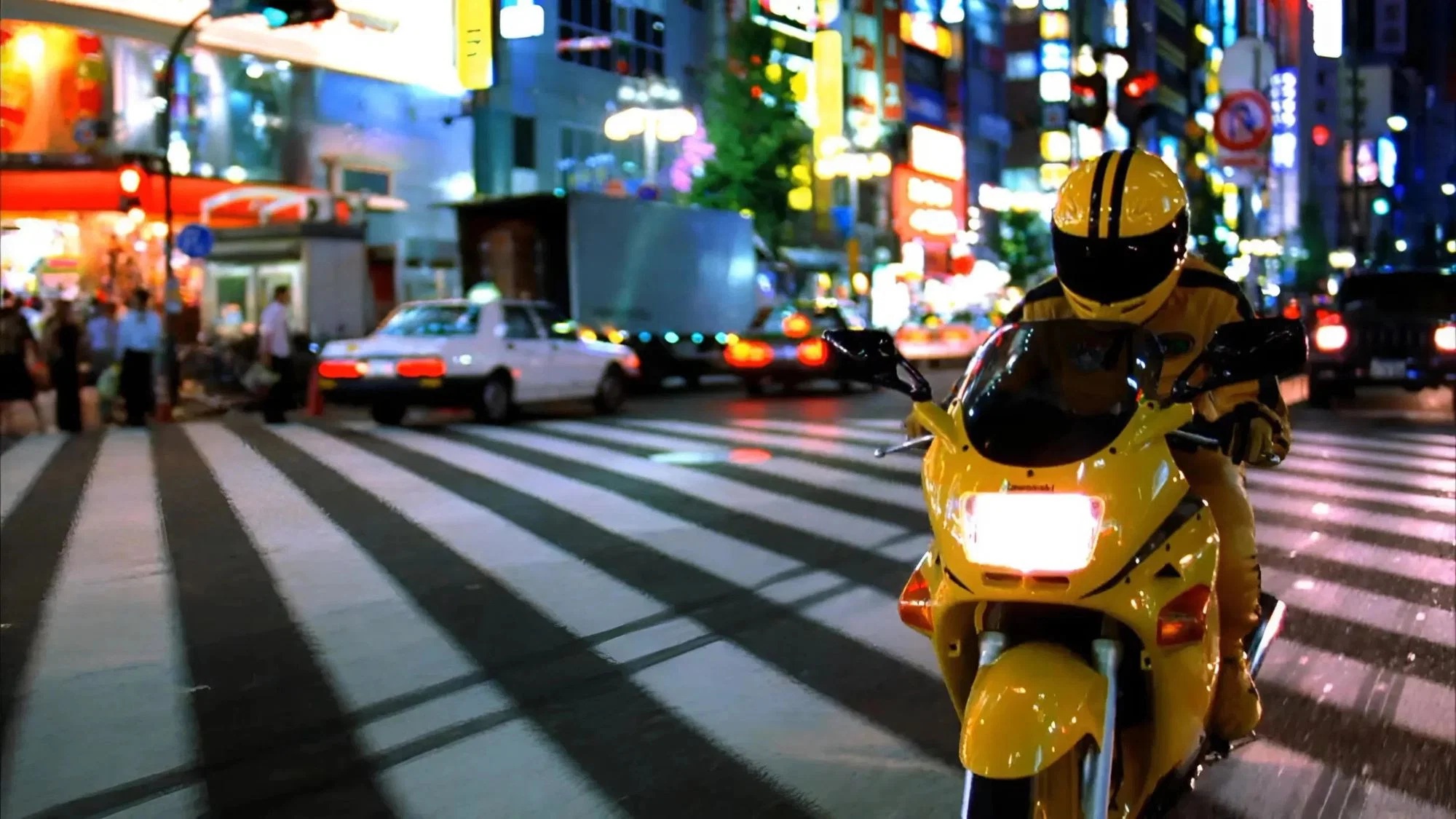 Die Braut fährt mit gelbem Anzug ein gelbes Motorrad über die Straßen von Tokio | Kill Bill: The Whole Bloody Affair
