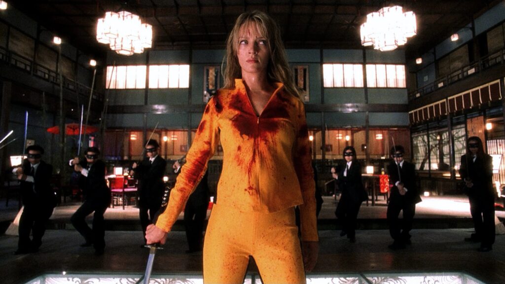 Die Braut steht kampfbereit im Vordergrund, während im Hintergrund mehrere maskierte Schwertkämpfer zu sehen sind. | Kill Bill: The Whole Bloody Affair