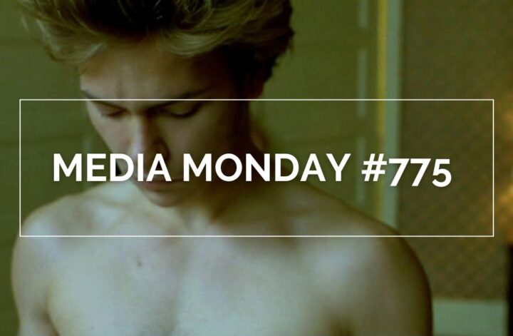 River Phoenix in „My Private Idaho“ in einer ruhigen Innenraumszene: mit kurzem, hellem Haar und gesenktem Blick steht er oberkörperfrei im warmen Licht eines Zimmers mit Tapete, Tür und Lampe im Hintergrund. Die Aufnahme betont die verletzliche, melancholische Stimmung des queeren Roadmovies.