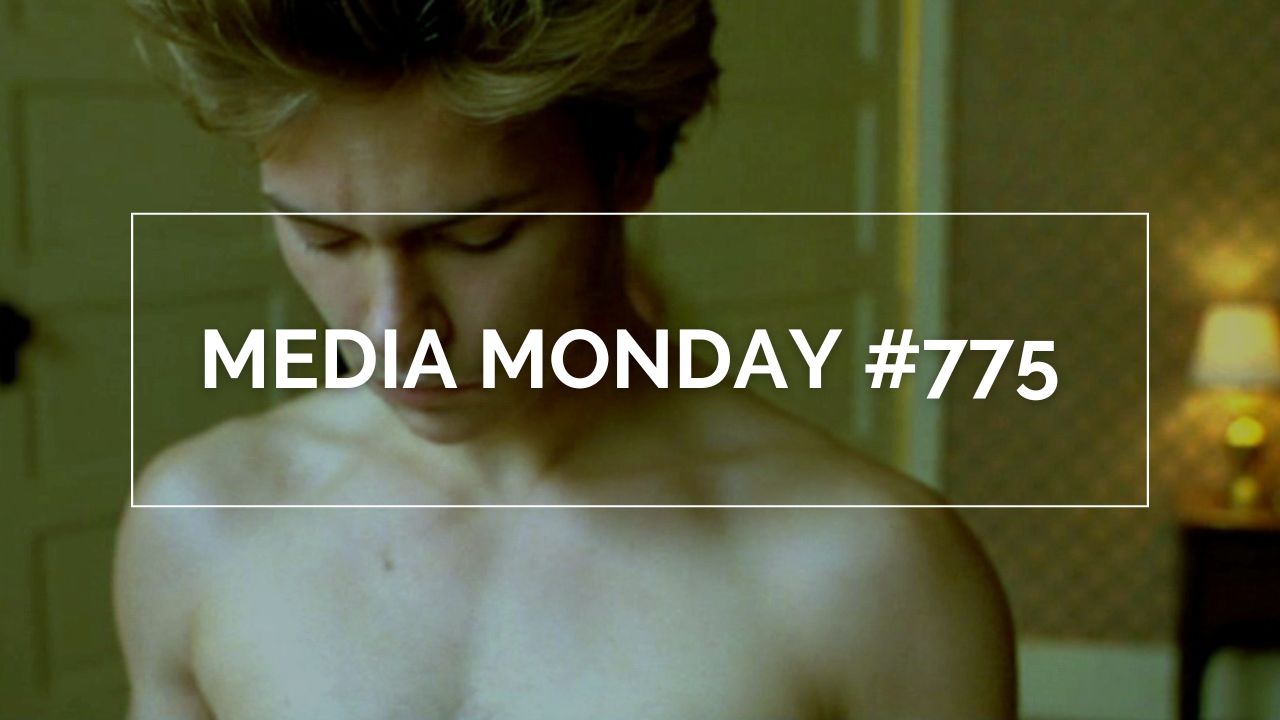 River Phoenix in „My Private Idaho“ in einer ruhigen Innenraumszene: mit kurzem, hellem Haar und gesenktem Blick steht er oberkörperfrei im warmen Licht eines Zimmers mit Tapete, Tür und Lampe im Hintergrund. Die Aufnahme betont die verletzliche, melancholische Stimmung des queeren Roadmovies.