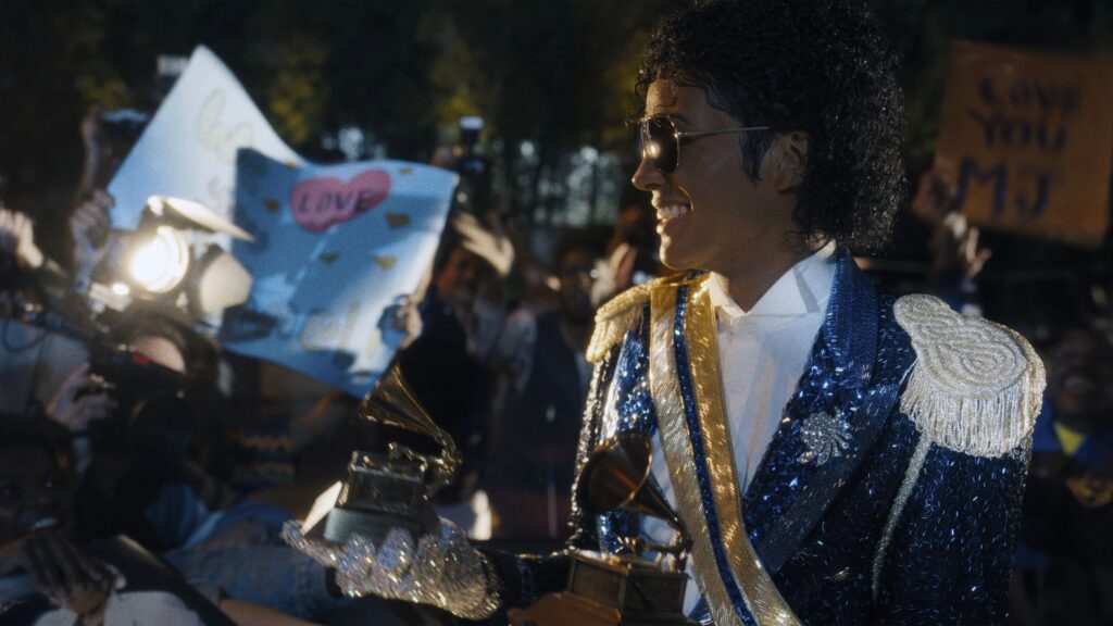 Michael (Jaafar Jackson) steht in einem glitzernenden Outfit vor einer Gruppe Fans und hält einen Grammy in der Hand