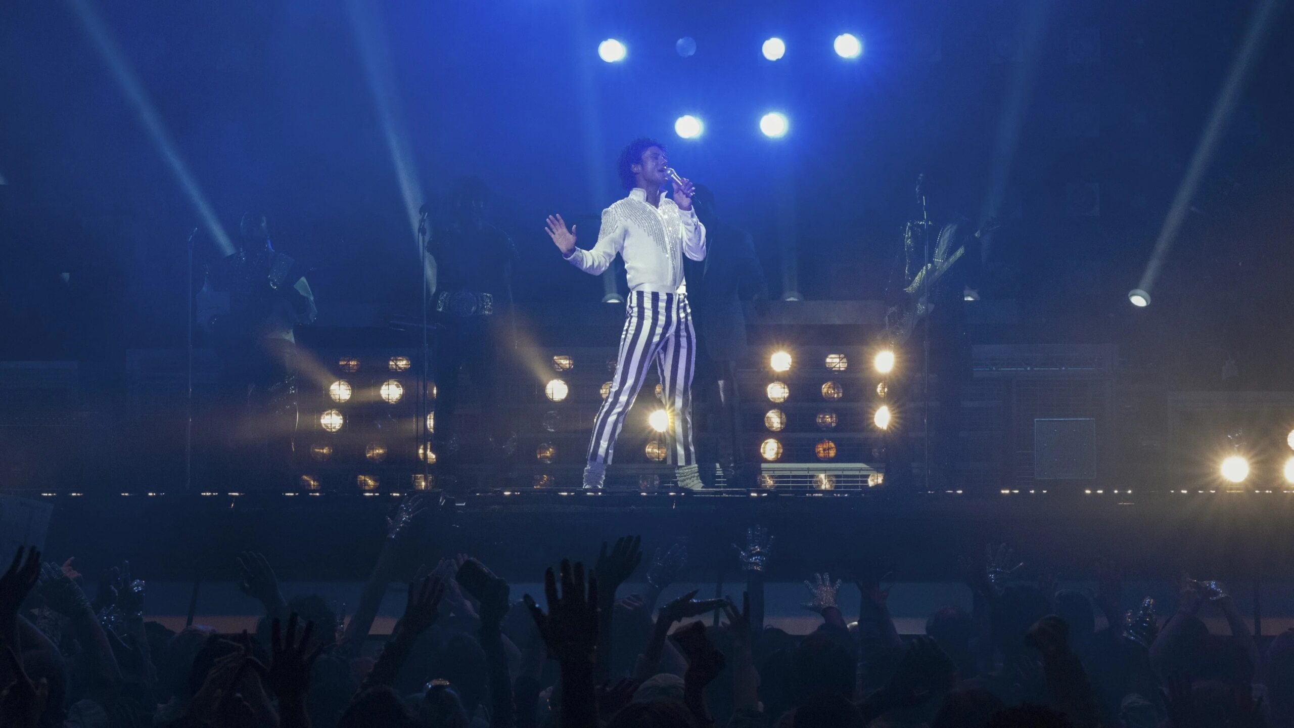 Michael (Jaafar Jackson) steht auf einer Bühne und singt vor einer Gruppe Fans