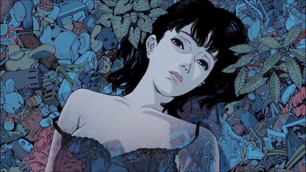 Mima Kirigoe (gesprochen von Junko Iwao) aus dem Anime‑Thriller „Perfect Blue“, liegend inmitten eines chaotischen Meeres aus Spielzeugen, Alltagsgegenständen und Erinnerungsstücken; eine ruhige, nach innen gekehrte Momentaufnahme, die ihre innere Zerrissenheit und den psychologischen Druck der Handlung widerspiegelt. | Themenübersicht Juni 2026 – Die 5 BESTEN am DONNERSTAG