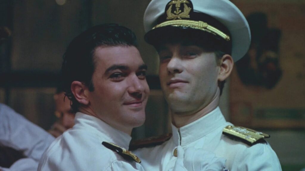 Tom Hanks und Antonio Banderas in Matrosenuniform tanzen eng umschlungen und lächeln dabei in die Kamera - Eine Szene aus "Philadelphia" (1993) | Die 5 besten Justiz- und Gerichtsfilme