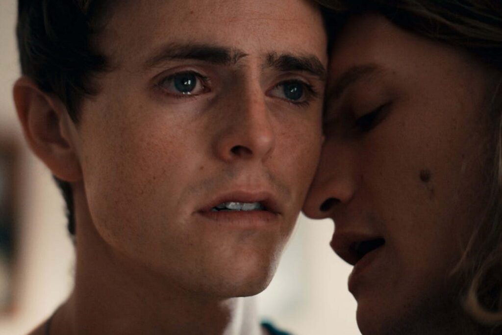 Dakota Riley (Jake Holley) und Skylar Braxton (Riley Quinn Scott) in einer Nahaufnahme aus dem Film „Riley“: Dakota blickt nach vorn, während Skylar sich dicht an ihn lehnt und ihm etwas ins Ohr sagt. Die Szene wirkt intim, verletzlich und spiegelt Dakotas inneren Konflikt zwischen Fassade und Wahrheit wider. | Media Monday #775