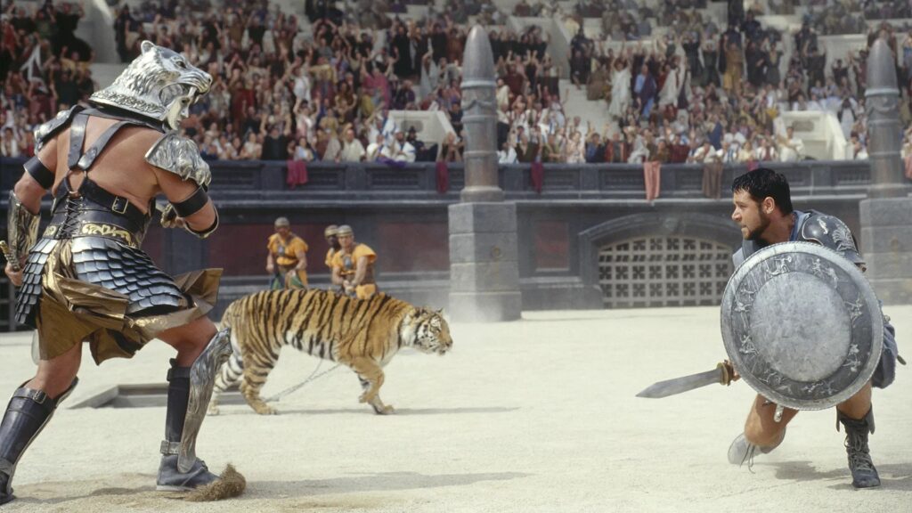 Zwei Gladiatoren stehen sich im Kollosseum gegenüber, hinter ihnen lauert ein Tiger | Die 5 besten Filme über die Antike