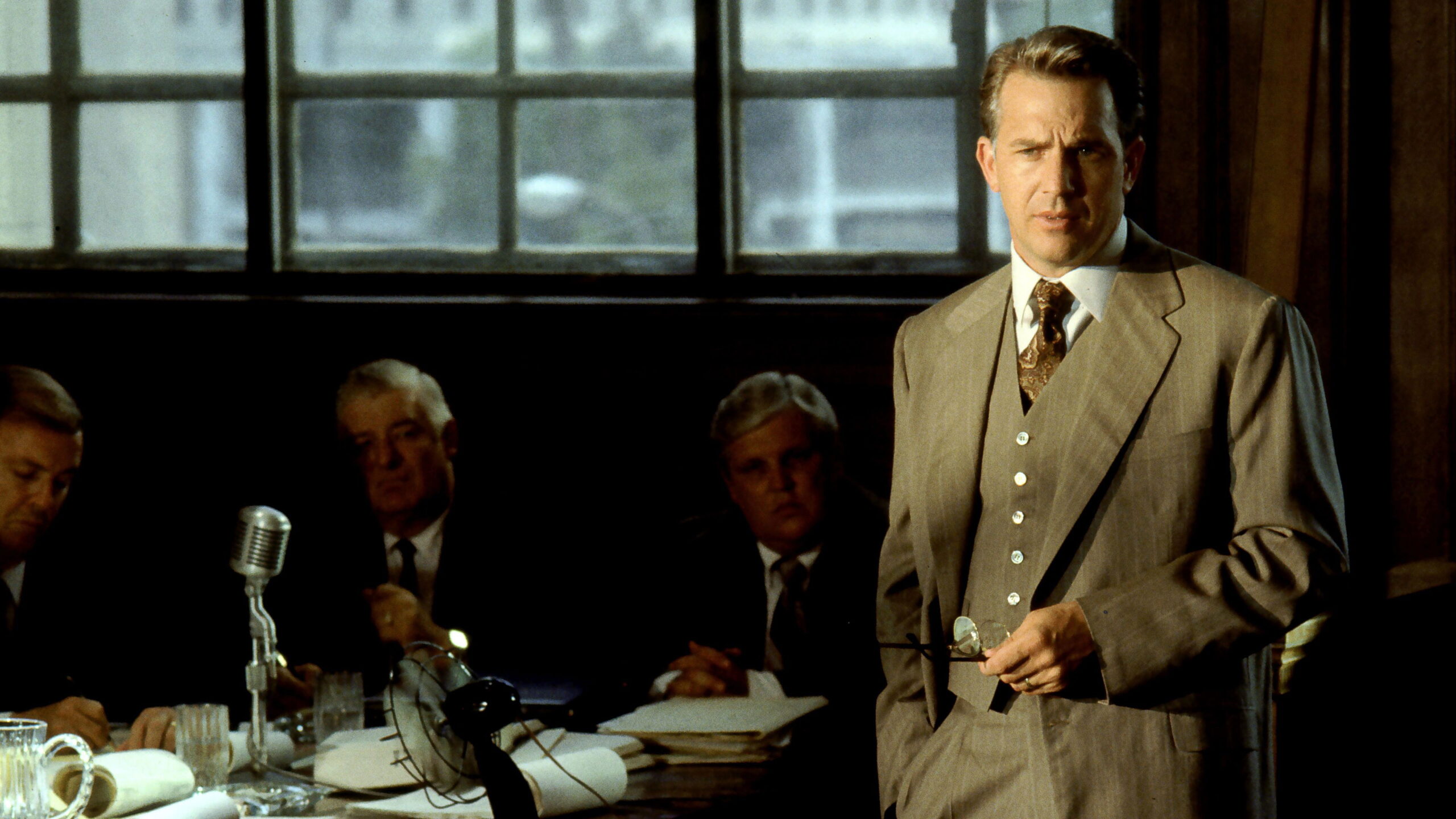 Das Bild zeigt Kevin Costner in einem Anzug in einem Gerichtssaal stehend in einer Szene des Films JFK: Tatort Dallas. Top 5 Filme über 180 Minuten