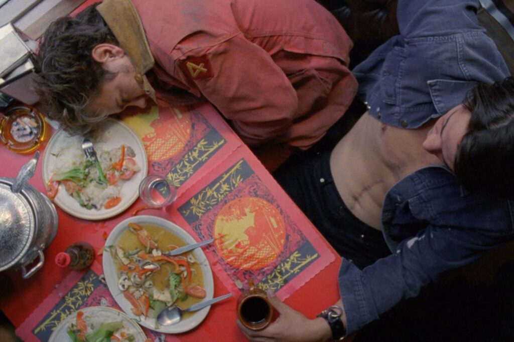 Mike (River Phoenix) und Scott (Keanu Reeves, rechts) aus My Private Idaho, von oben in einem asiatischen Restaurant fotografiert. Mike wirkt müde und hat den Kopf auf die Tischplatte gelegt, eingekuschelt in seine hellrote Jacke. Scott sitzt lässig, oben ohne aber mit Jeansjacke nach hinten gelehnt und hält eine Kaffeetasse fest | Media Monday #780