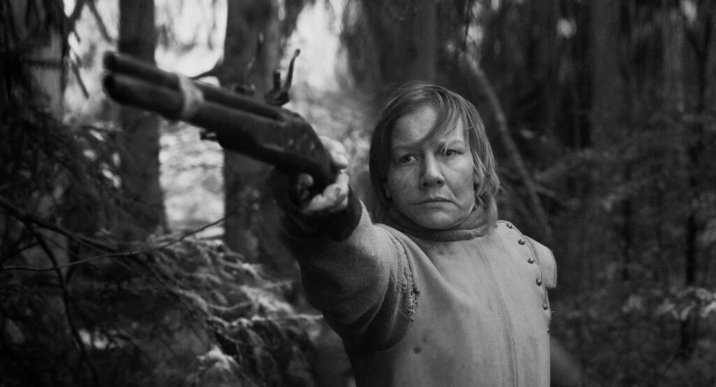 Das schwarz-weiß Bild zeigt Sandra Hüller mit einer Pistole in einer Szene des Films Rose.