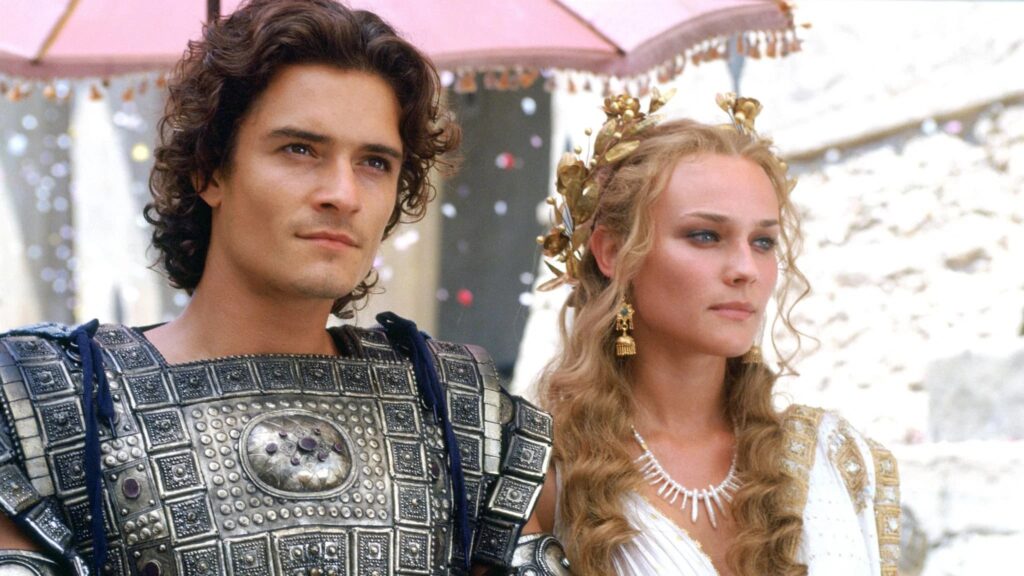 Helena (Diane Kruger) und Paris (Orlando Bloom) schauen in die Ferne, hinter ihnen ein rosaner Sonnenschirm