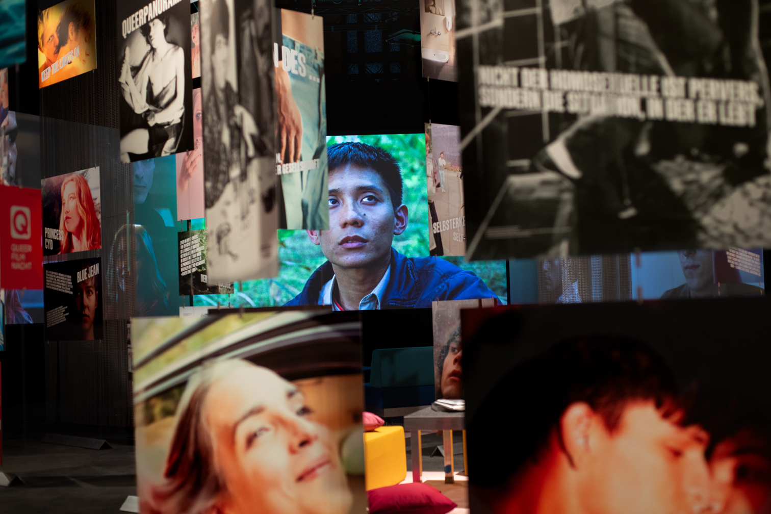 Foto der Ausstellung Inventing Queer Cinema in der Deutschen Kinemathek. Bilder aus verschiedenen Filmen hängen im Raum.