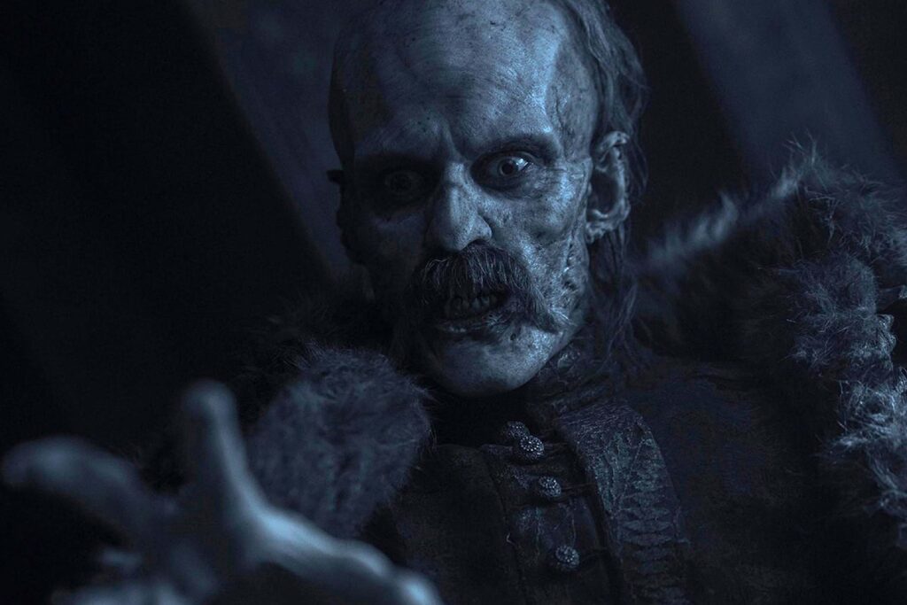 Bill Skarsgård als Dracula in Nosferatu – Der Untote mit blassem, verwesendem Gesicht, eingefallenen Augen und dunklem Schnurrbart. Die Nahaufnahme zeigt ihn in dunkler, historisch anmutender Kleidung mit Fellbesatz, während das kalte, bläuliche Licht seine unheimliche, übernatürliche Präsenz betont. | Media Monday #787